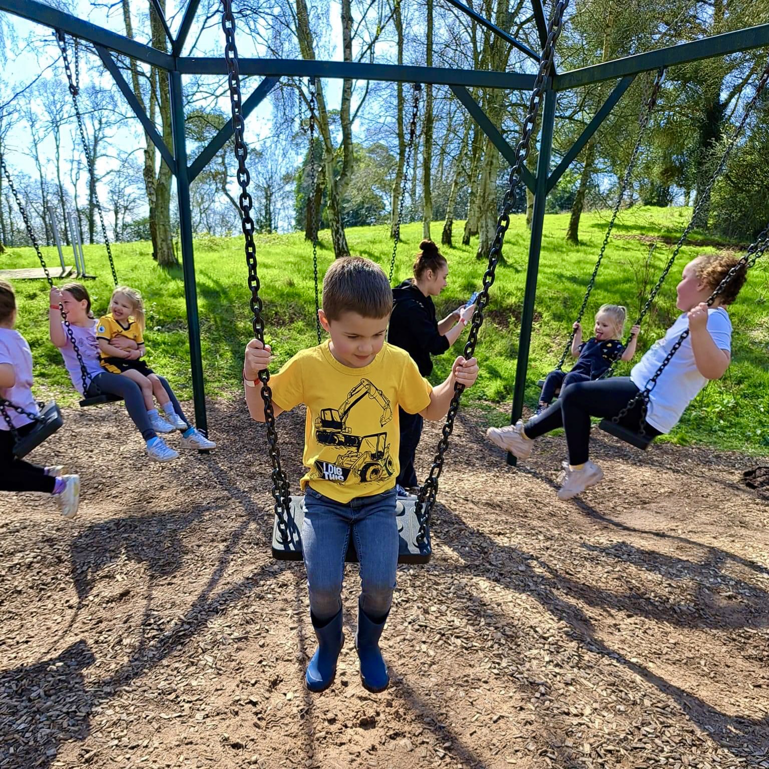 Happy family enjoying the giant wooden swing on Habberley Trail in Kidderminster overlooking Worcestershire valley