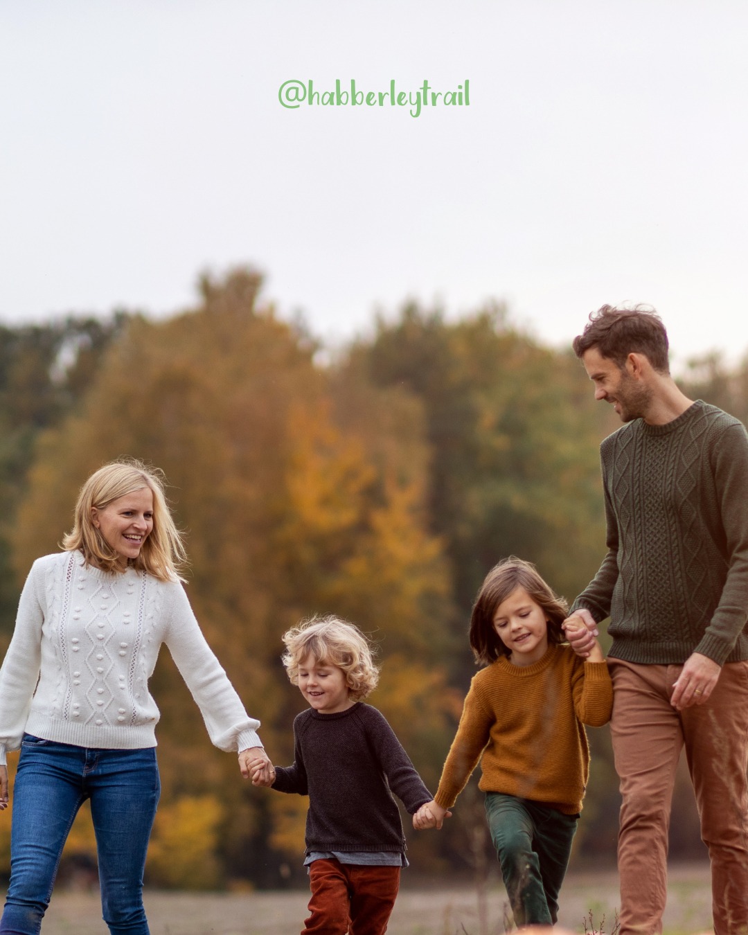 Candid outdoor family walking together holding hands along a lush green forest adventure trail path
