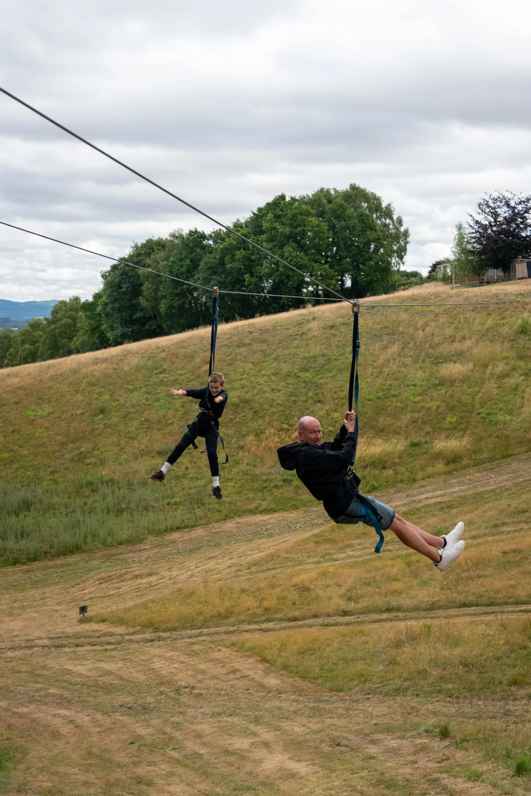 Excited child riding scenic zip wire across lush English woodland